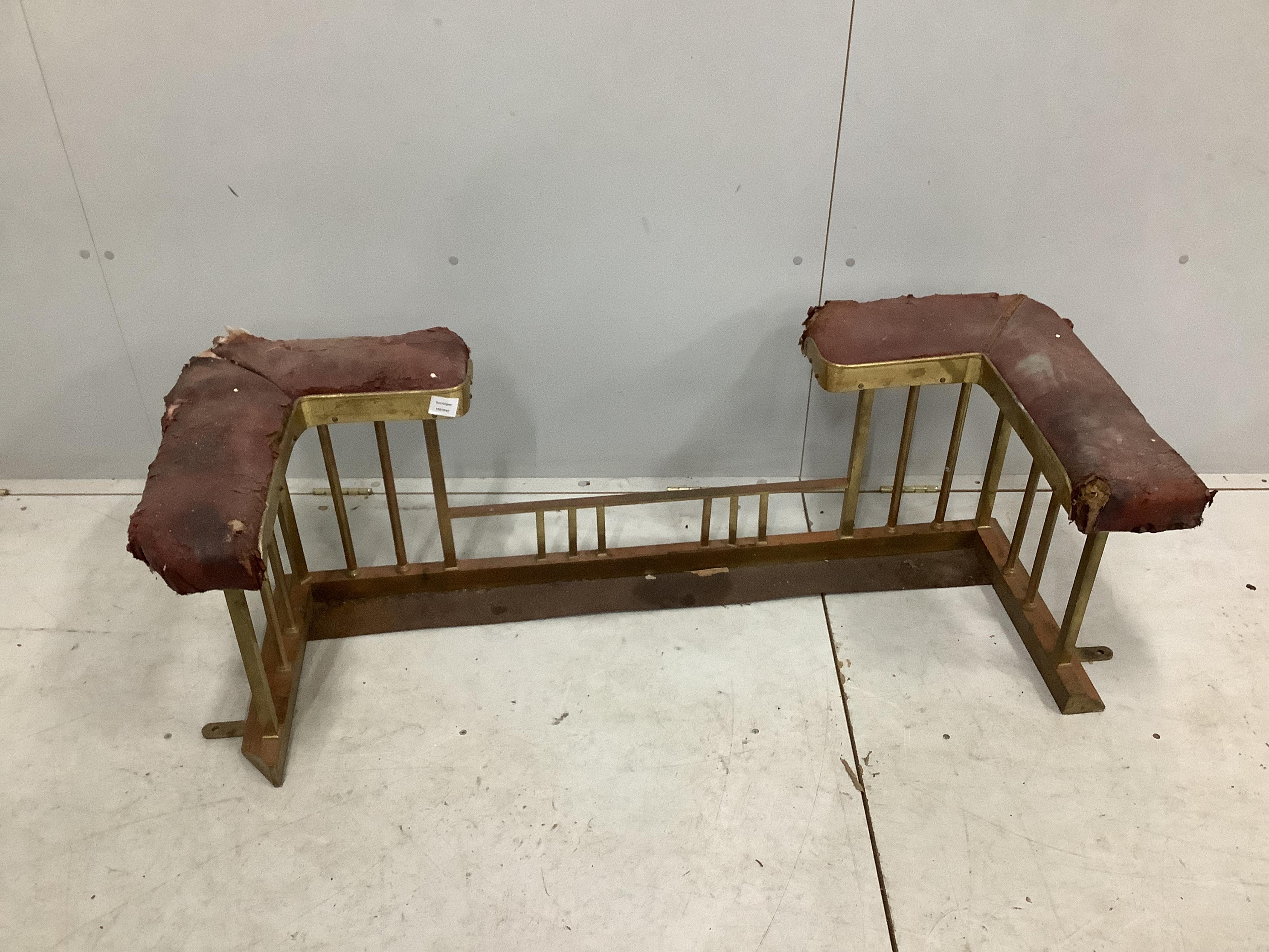 An Edwardian iron and brass club fender, width 128cm, depth 50cm, height 44cm. Condition - poor and in need of restoration, red leather seats will need replacing, metalwork tarnished, rear right side cut to accommodate a